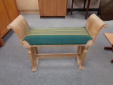 A blonde oak duet stool with under stretcher upholstered in a green striped fabric