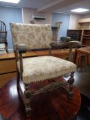 A carved armchair upholstered in a floral tapestry fabric