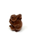 A carved Chinese hardwood netsuke - Rabbit seated on fruit