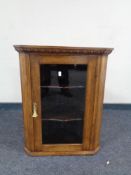 An Edwardian oak hanging corner cabinet with glazed door