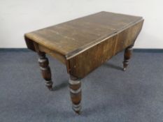An Edwardian oak flap sided kitchen table