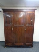 A late Victorian mahogany single door wardrobe raised on shepherd's castors