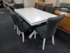 A contemporary white extending dining table on pedestal and six chairs in grey fabric