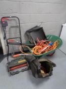 A wheelbarrow containing electric hedge trimmer, extension leads, one 10V extension lead,