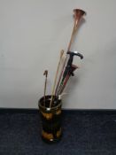 A glazed ceramic stick stand containing copper and brass hunting horns, riding crop,