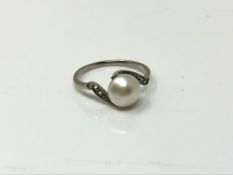 An early twentieth century platinum ring set with a pearl and diamond shoulders, size I.