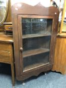 A glazed door corner cabinet on raised legs