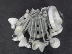 A circular metal light fitting fitted with sixteen angle poise lamps