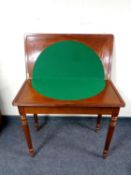A reproduction mahogany turnover top card table
