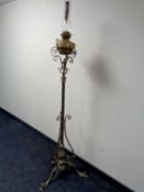 An ornate brass oil standard lamp with etched frosted glass shade and brass reservoir