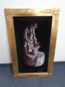 A gilt framed oil painting on fabric depicting a blacksmith