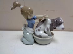 A Lladro figure of a girl washing hound in tub.