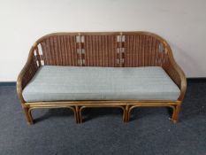 A contemporary wicker three seater conservatory settee