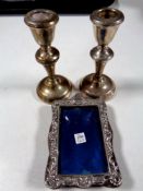 A pair of silver candlesticks together with a silver photo frame