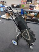 An electric golf cart together with a St Andrews golf bag containing irons and drivers
