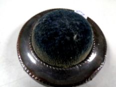 A circular silver pin cushion