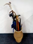A ceramic and wicker vase containing a large quantity of walking sticks and walking canes to