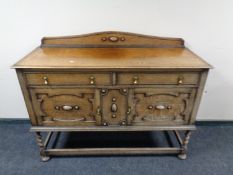 An Edwardian carved oak sideboard on barley twist supports