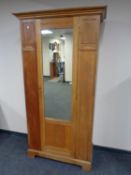 An Edwardian oak mirror door wardrobe
