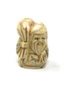 A carved bone netsuke - Elderly man carrying money bag
