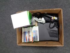 A box containing an X Box 360 with accessories and games