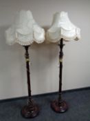 A pair of stained beech standard lamps with shades