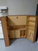 A teak effect double door ship's style cabinet containing bureau and shelves