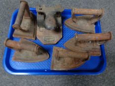 A tray containing vintage punch together with five cast iron flat irons