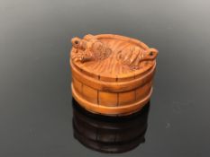 A carved hardwood netsuke - turtles in a barrel