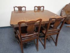 An early 20th century carved oak pull out dining table on bulbous legs together with a set of four