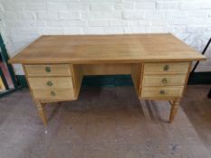 A blonde oak twin pedestal desk fitted six drawers