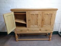 A continental blonde oak triple door sideboard fitted three drawers on raised legs