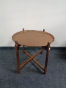 A copper scalloped edge occasional table on folding base