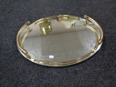 An oval contemporary mirrored serving tray with brass handle and gallery