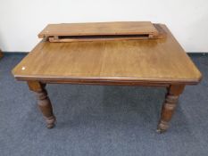 An Edwardian mahogany wind out dining table with two leaves