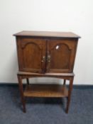 An Edwardian oak double door cabinet on raised legs with under shelf fitted two internal drawers