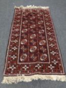 A fringed Afghan Bokhara rug on red ground,