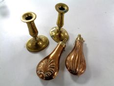 Two antique copper powder flasks together with a pair of antique brass candlesticks