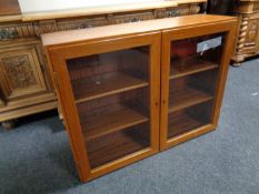 A mid century teak double door glazed cabinet