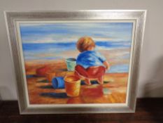 A contemporary silvered framed oil on canvas depicting a boy playing on a beach