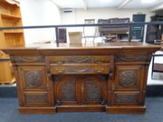 An Arts and Crafts heavily carved oak break front sideboard fitted drawers and cupboards beneath