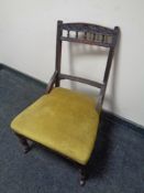 An Edwardian nursing chair upholstered in a gold fabric.