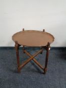 A copper scalloped edge occasional table on folding base