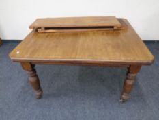 An Edwardian mahogany wind out dining table with two leaves