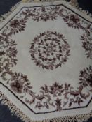 A hexagonal floral fringed rug on cream ground.