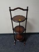 A mahogany three tier folding cake stand