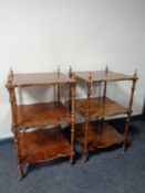 A pair of shaped three tier whatnot stands on brass casters in a walnut finish