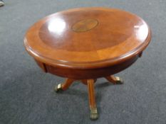 A circular pedestal coffee table on brass capped feet