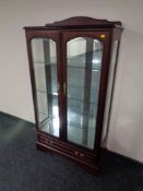 A contemporary double door display cabinet fitted drawer beneath in a mahogany finish