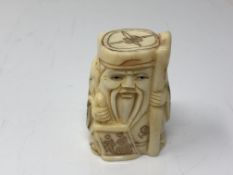 A carved Chinese bone netsuke - Gentleman carrying a staff and scroll